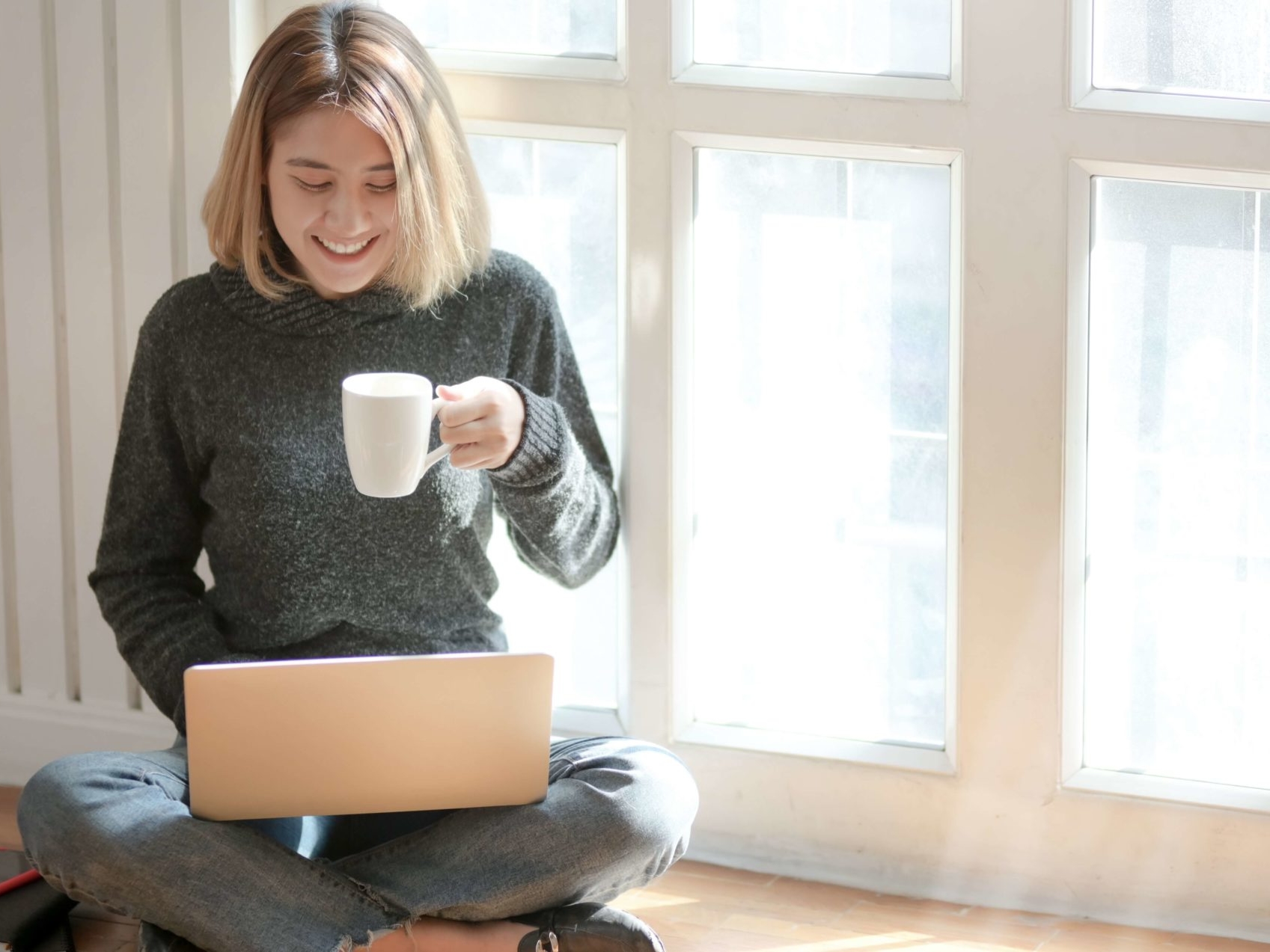 woman drinking coffee looking at computer